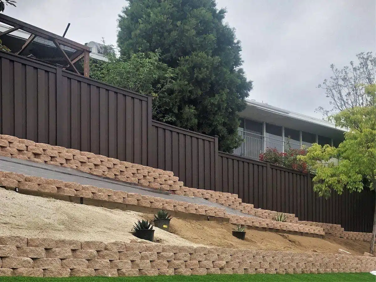 A Woodland Brown Trex Fence above tiered retaining walls in Southern California backyard