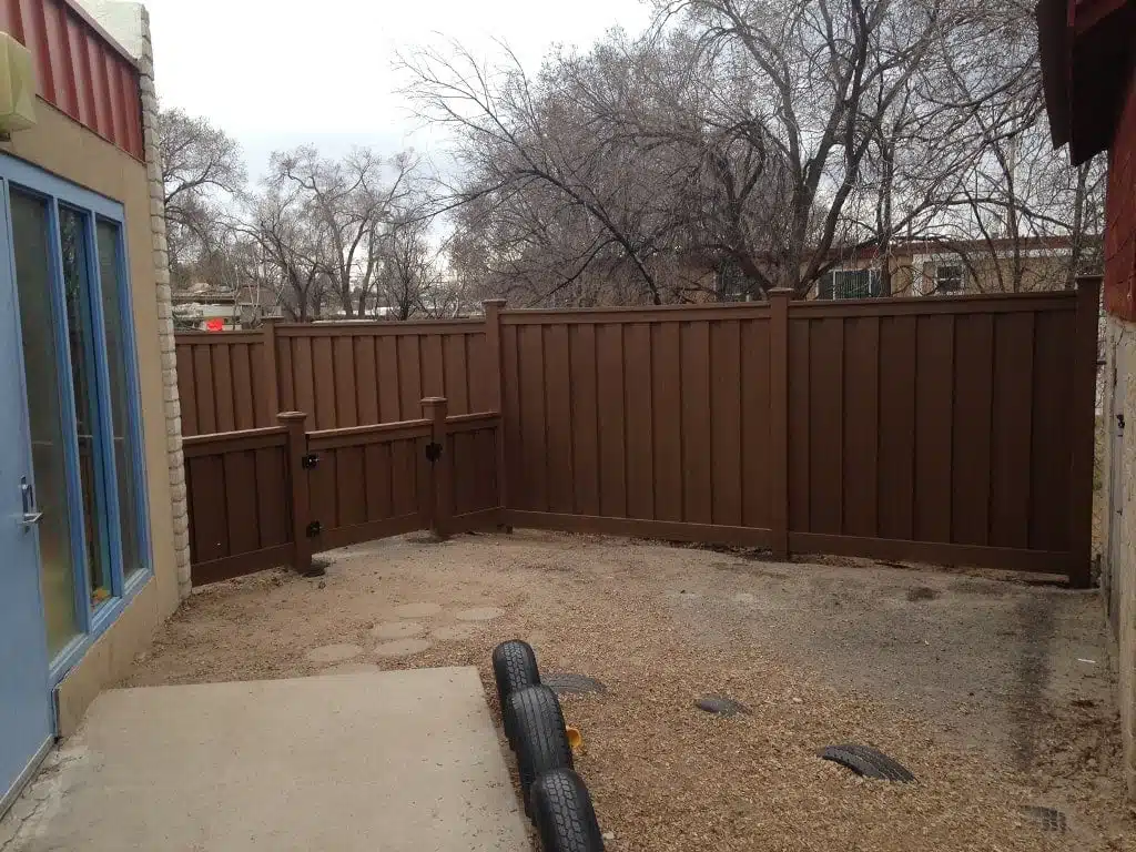 A small Trex gate and fence separating play areas in an early childhood development center's backyard.
