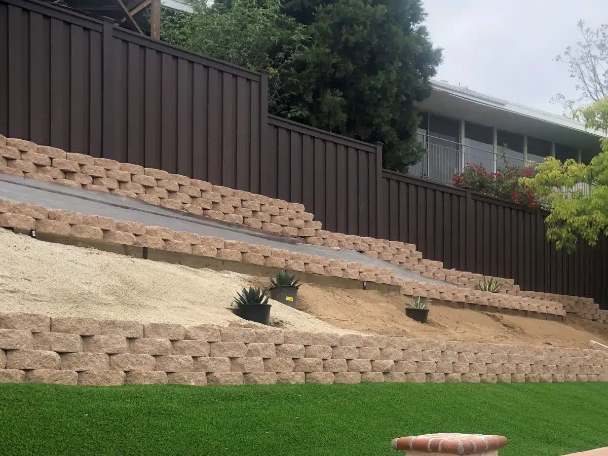 A Trex Fencing providing a backdrop to a terraced backyard. The terraced walls are made from landscaping blocks.