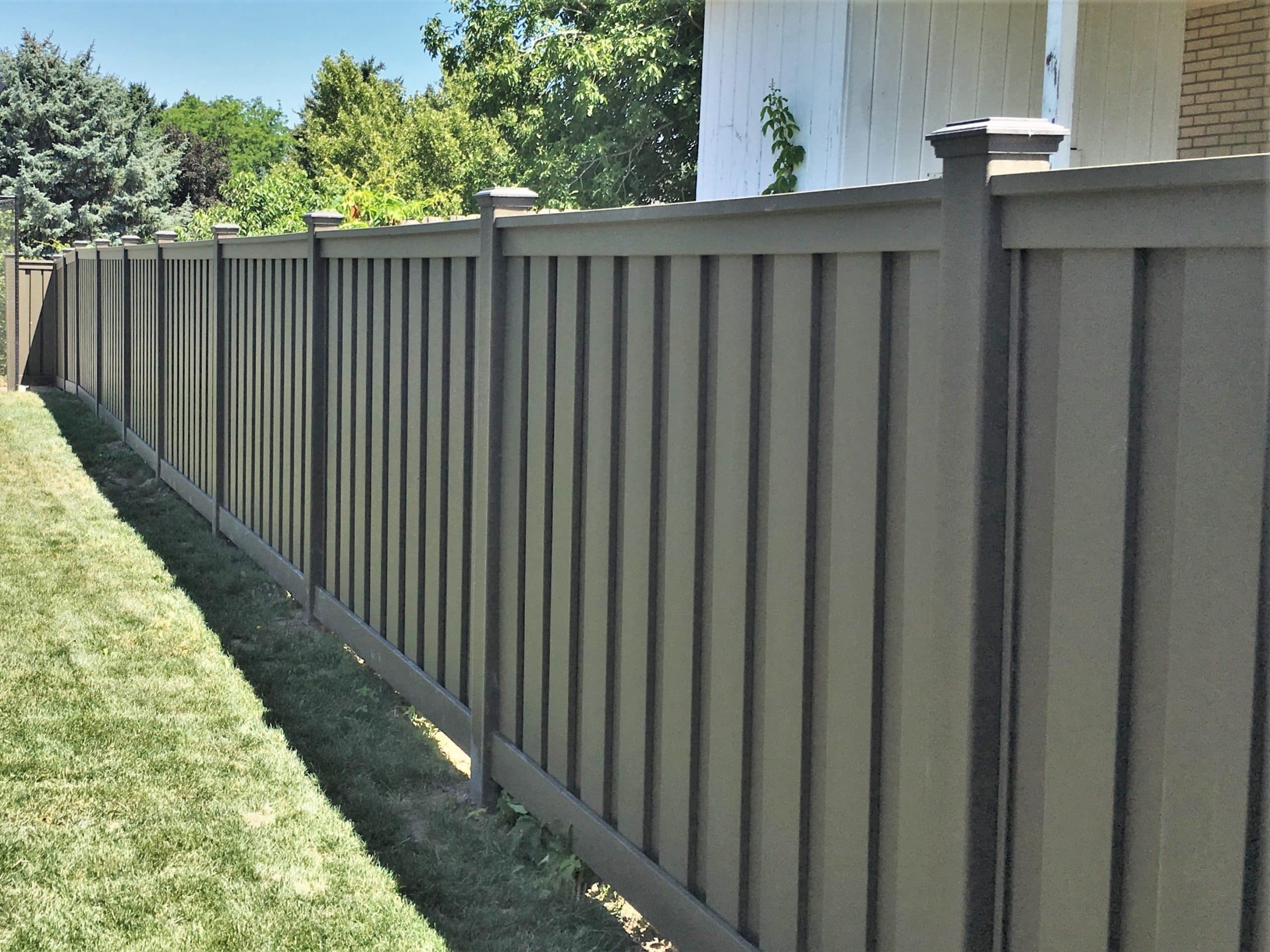 Fence panels made of Trex Seclusions privacy fencing installed along the property line of a backyard.
